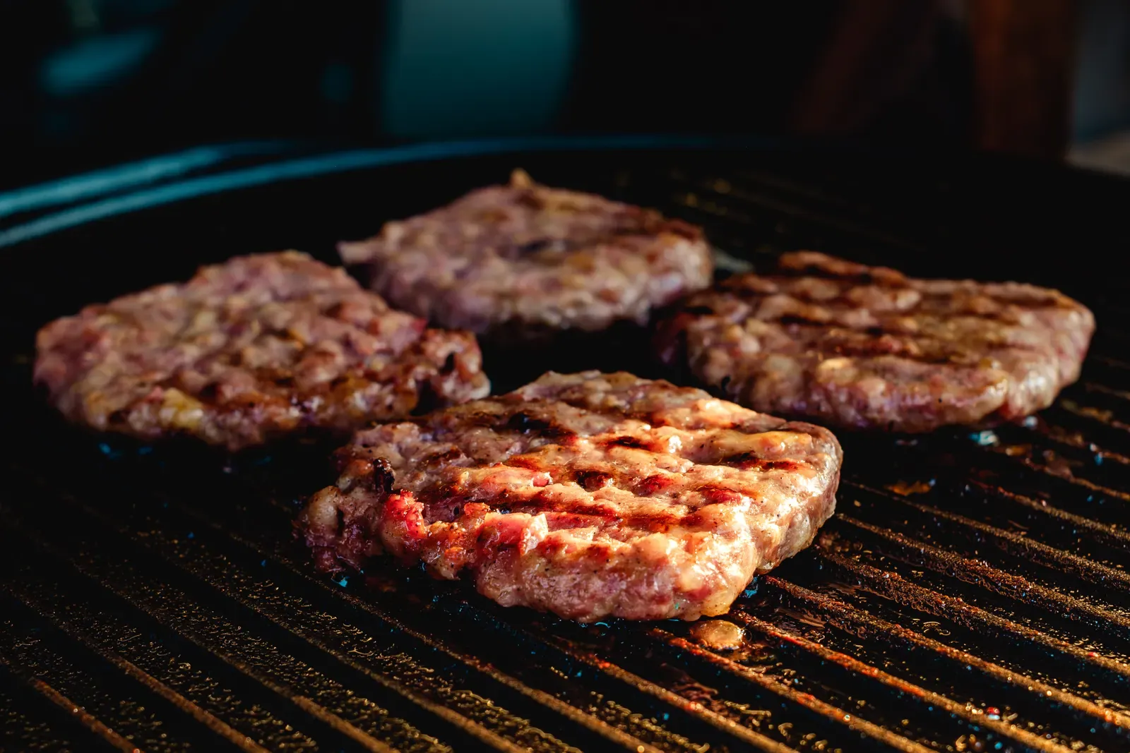 Burger patties sizzling on a barbecue grill, ground meat that must reach 160 degrees