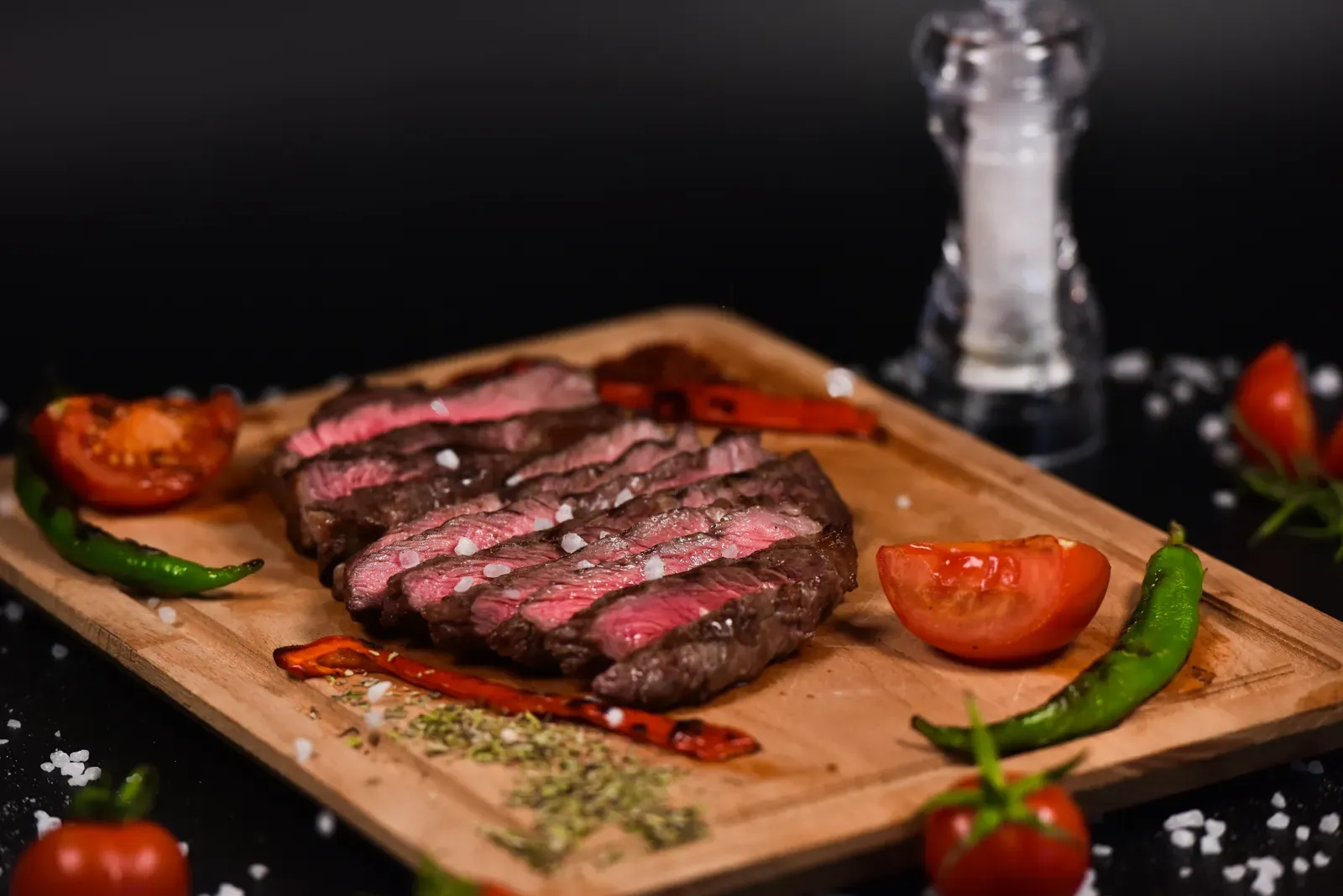Sliced medium-rare steak arranged on a wooden cutting board
